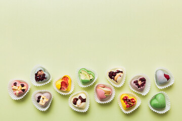 chocolate sweets in the form of a heart with fruits and nuts on a colored background. top view with space for text, holiday concept