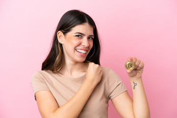 Young Italian woman holding a Bitcoin isolated on pink background celebrating a victory