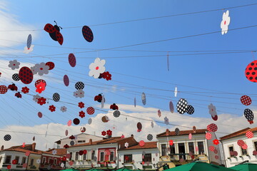 Colorist decoration of red-black-white images of flowers and dotted ladybugs hanging over the Old Bazaar Sheshi Iliria Square. Korca-Albania-252