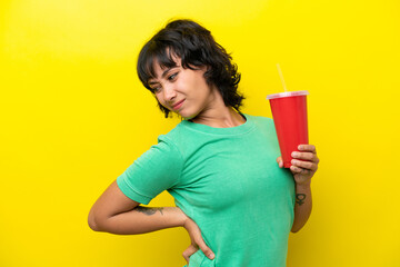 Young Argentinian woman holding a soda isolated on yellow background suffering from backache for...