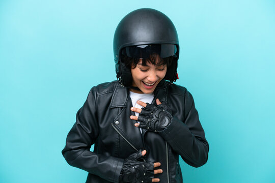 Young Argentinian woman with a motorcycle helmet isolated on blue background smiling a lot