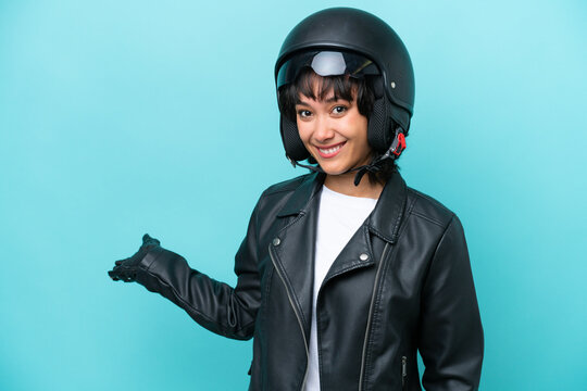Young Argentinian woman with a motorcycle helmet isolated on blue background extending hands to the side for inviting to come