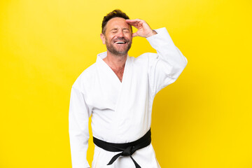 Middle age caucasian man doing karate isolated on yellow background smiling a lot