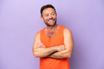 Middle age caucasian man isolated on purple background with arms crossed and looking forward