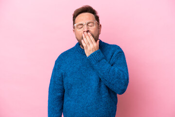 Middle age caucasian man isolated on pink background yawning and covering wide open mouth with hand