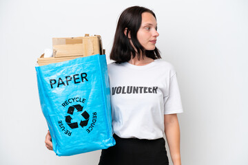 Young caucasian woman holding a recycling bag full of paper to recycle isolated on white background looking to the side