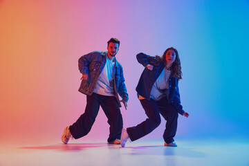 Male and female dancers performing hip-hop dance in motion against gradient blue-yellow background...