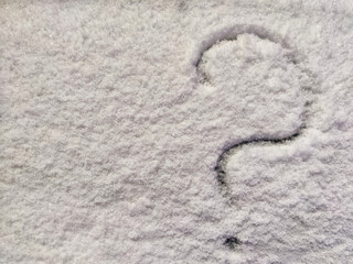 A question mark written in the snow. The cold frosty texture of the snow and the question mark. Background, place for text, copy space