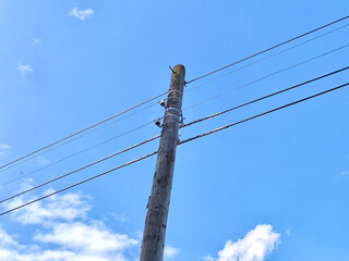 Old power line pole against blue sky in sunny day