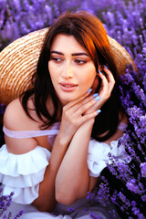  A woman in white dress and straw hat the lavender field on sunset.