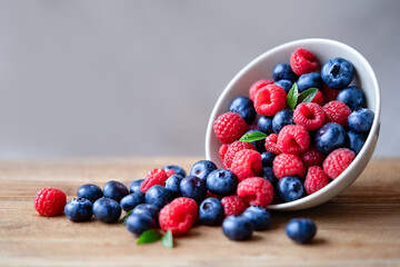 Raspberries and blueberries on a wooden table. Raspberries and blueberries in a bowl. Healthy food