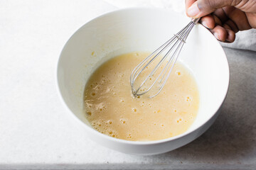 Whisking eggs and sugar together until pale, mixing eggs and sugar by hand, process of making a cake