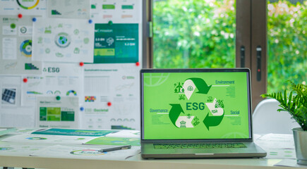 ESG ( environment, social,governance) recycle sign on laptop screen with carbon free chart board in...