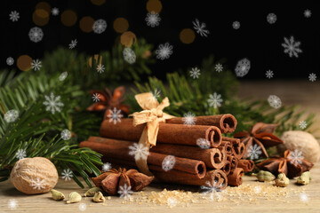 Different spices and fir tree branches on wooden table, closeup. Cinnamon, anise, cardamom, nutmegs