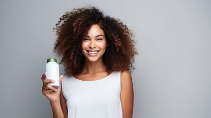 closeup of beautiful young model woman with curly hair holding bottle of shampoo or conditioner hair product. Mock up, advertising for care and beauty hair product. Concept promotion cosmetic product - obrazy, fototapety, plakaty