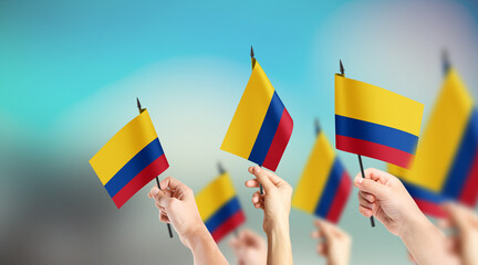 A group of people are holding small flags of Colombia in their hands.