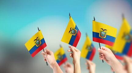 A group of people are holding small flags of Ecuador in their hands.