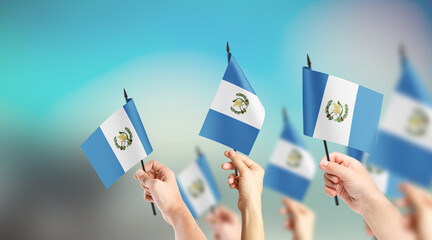 A group of people are holding small flags of Guatemala in their hands.