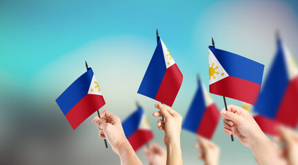 A group of people are holding small flags of Philippines in their hands.
