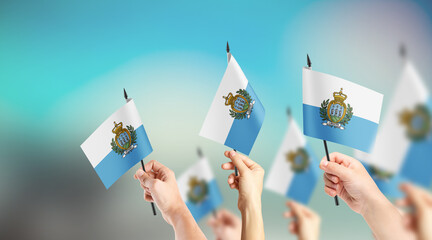 A group of people are holding small flags of San Marino in their hands.