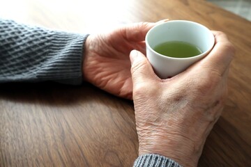 湯呑を持つ高齢女性の手元