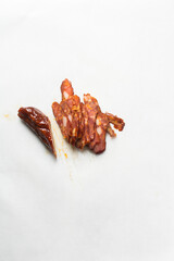 Slicing chinese sausage on a white chopping board, lap cheong sausage being cut into thin slices on white background