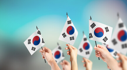 A group of people are holding small flags of South Korea in their hands. - obrazy, fototapety, plakaty