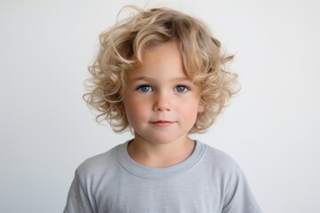 Portrait of cute little blond boy with curly hair looking at camera