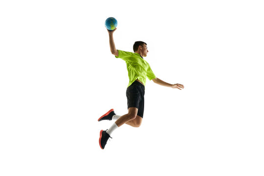 Dynamic image of young man in uniform, handball player in motion during game, practicing, jumping with ball against white studio background. Concept of professional sport, tournament, competition