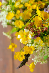 Fototapeta premium Small yellow wild flowers close up in meadow bouquet, mix of summer herbs and grass, floral vertical photo