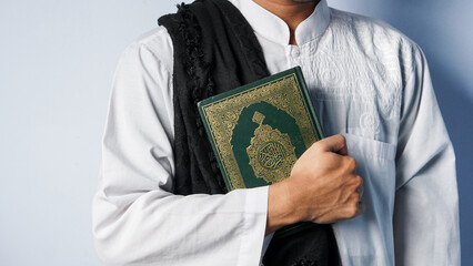 A Muslim man carries the Quran in both hands. concept of the month of Ramadan