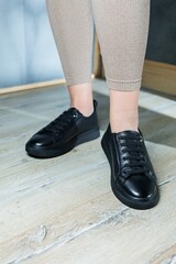 Collection of women's shoes. Black leather sneakers on women's feet. Female feet in comfortable casual sandals