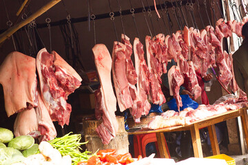 Meat market in China. Raw meat hanging on hooks outdoor. Raw pork and beef. Butchers shop background. Street market in Asia.