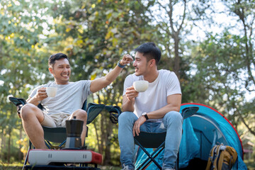 Male gay couple asian traveling with tent camping outdoor and various adventure lifestyle hiking active summer vacation. drinking coffee and talking together