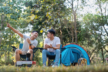 Male gay couple asian traveling with tent camping outdoor and various adventure lifestyle hiking active summer vacation. drinking coffee and talking together