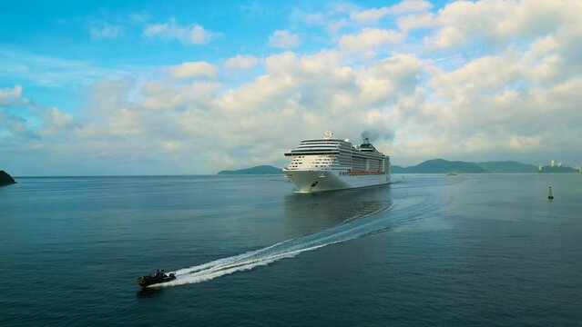 Santos, Brazil, December 2023: Cruise liner sailing. People on the upper deck celebrates vacation. 4K aerial view of shipboard of the cruise ship leaving terminal. Water transportation.

