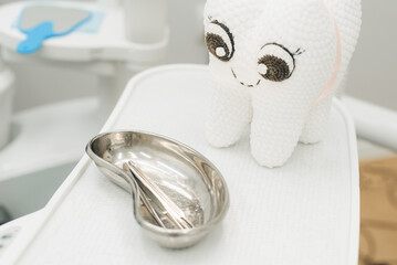 A plush tooth, a mirror and dental tools in the dentist's office.