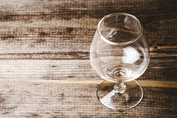 Empty brandy glass on rustic wood. Cognac alcohol background. Antique wooden plank with alcohol...