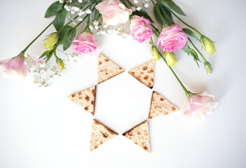  Passover.  Traditional Matzo shape of star Magen David decorate by pink flowers on white background. top view. Holiday of Jewish people, Spring Holiday. Fasting time