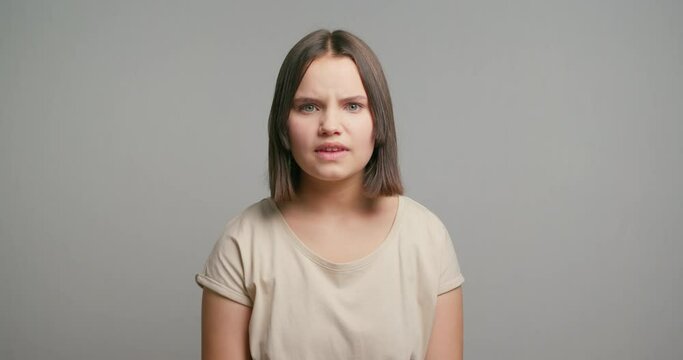 Picture of angry young latin woman screaming isolated over gray background. Looking at camera
