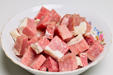 Pork cut into pieces in a bowl to be cooked.
