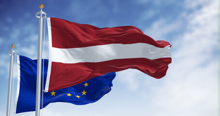 Flags of Latvia and the European Union waving on a clear day. Latvia is a member of the European...