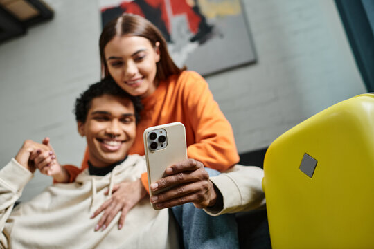 focus on smartphone happy diverse couple browsing internet near luggage in hostel room