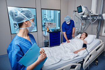 ICU. Hospital technicians visiting and caring female patient in intensive care - obrazy, fototapety, plakaty