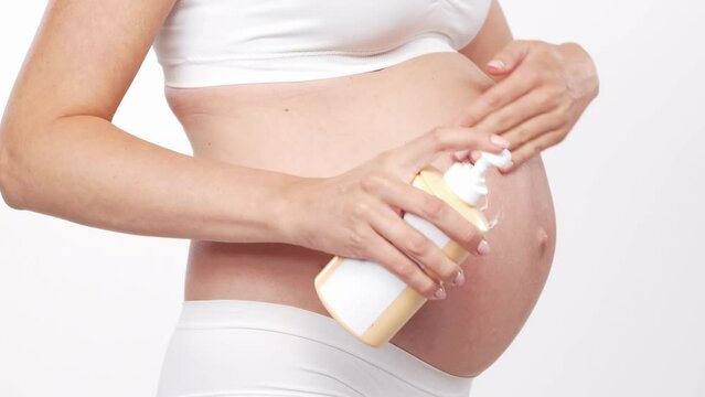 Young, happy and healthy pregnant woman in front of white background. Studio video. Baby expectation, pregnancy and motherhood.