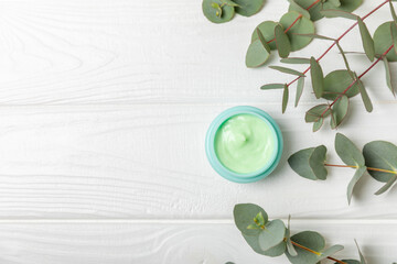 Jar of moisturizing cosmetic cream for face, hands and body with eucalyptus leaves on a white...