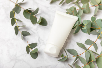 Jar of moisturizing cosmetic cream for face, hands and body with eucalyptus leaves on marble...