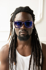 portrait of a stylish African man with dreadlocks wearing sunglasses