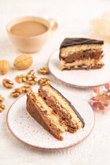 Chocolate biscuit cake with caramel cream and walnuts on gray concrete. side view, selective focus