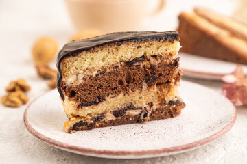 Chocolate biscuit cake with caramel cream and walnuts on gray concrete. side view, selective focus